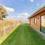 Holzhaus mit grünem Rasen und Zaun entlang des Grundstücks.