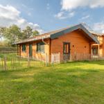 Holzhaus mit Grasdach und Holzzaun auf grünem Grundstück