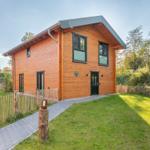 Holzhaus mit grünem Dach und Gartenweg. Umgeben von Gras und Bäumen.