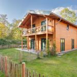 Holzhäuschen mit Balkon und Garten. Terrasse mit Tisch und Stühlen.