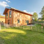 Holzhaus mit Garten und Terrasse. Umzäunt mit Holzpfostenzaun.