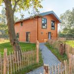 Holzhaus mit Garten und Steintreppe. Holzgeviert und grüner Rasen.