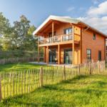 Holzhaus mit Balkon und Gartenzaun im Grünen