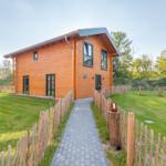 Holzhaus mit Garten und Steintreppe. Modernes Design mit großen Fenstern.
