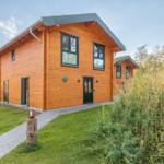 Holzhaus mit grüner Umgebung und gepflastertem Weg.