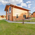 Holzhäuser mit Garten und Terrasse unter blauem Himmel.