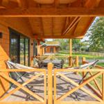 Terrasse mit Hängematten und Tisch unter Holzüberdachung.