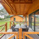 Terrasse mit Tisch, Stühlen und Hängematte. Holzveranda mit Blick auf Grünfläche.