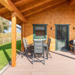 Terrasse mit Tisch, Stühlen und Hundehütte vor Holzhaus