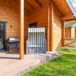 Holzterrasse mit Strandkörben und Gartenzaun. Hintergrund: weiteres Holzhaus.