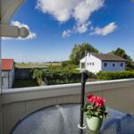 Terrasse mit Tisch und Blume, Blick auf Haus und Landschaft.