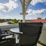 Terrasse mit zwei Stühlen und Tisch. Blick auf Straße und Gebäude.