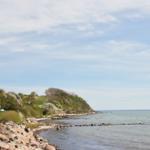 Strand mit Steinen und Grünflächen am Wasser