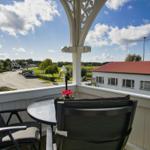 Terrasse mit Tisch und Stühlen, Blick auf Straße und Gebäude.