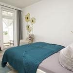 Schlafzimmer mit Bett, Stuhl und Fenster zur Terrasse.