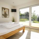 Schlafzimmer mit Doppelbett, TV und Blick auf Garten.