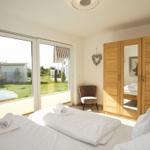 Zimmer mit Doppelbett, Holzschrank und Blick auf Garten