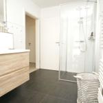 Badezimmer mit Dusche, Waschtisch und Heizkörper.