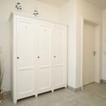 Eingangsbereich mit weißem Schrank, Pflanze und Wanddekoration.