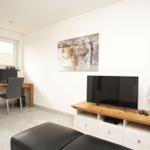 Wohnzimmer mit TV, Schreibtisch und Fenster. Wandbild und Beistelltisch.