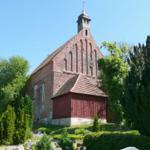 Historische Kirche mit rotem Dach und umliegenden Bäumen.