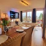 Esszimmer mit TV, Balkon und Kaminofen. Tisch gedeckt mit Tulpen.