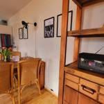 Essbereich mit Holztisch, Stühlen und Wandbildern. Radio auf Holzregal.