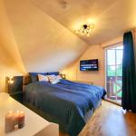 Schlafzimmer mit Dachschrägen, Bett, TV und Balkontür.