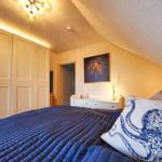 Schlafzimmer mit Bett, Kleiderschrank und Wandbild mit Oktopusmotiv.