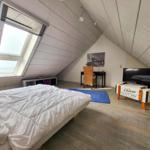 Schlafzimmer mit Dachfenster, Bett, Schreibtisch und TV.