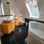 Badezimmer mit Dusche, Badewanne, Waschbecken und Toilette unter Dachschrägen.