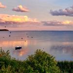 Sonnenuntergang über See mit Segelbooten und fliegenden Vögeln