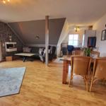 Wohn- und Essbereich mit Kamin, Holzboden und Sitzgelegenheiten.