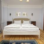 Schlafzimmer mit Doppelbett, Holzboden und Fenster. Zwei Nachttische und Wandbilder.