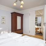 Schlafzimmer mit Bett, Kleiderschrank und Türen zu einem angrenzenden Raum.