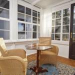 Terrasse mit zwei Rattanstühlen und Glas-Tisch auf Holzboden.