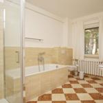 Badezimmer mit Badewanne, Dusche, Waschbecken und Fenster.