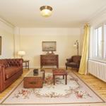 Wohnzimmer mit Ledersofa, Holzboden und Fenster mit Blick auf Grün.