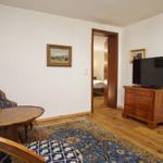 Wohnzimmer mit Holzboden, Teppich, TV und Sitzgelegenheit.