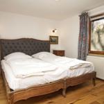 Ein Schlafzimmer mit einem großen Bett, Holzboden und einem Fenster mit Vorhängen.