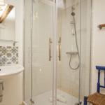 Bad mit Dusche, Waschbecken und blauer Stuhl.