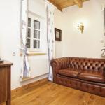 Ein Wohnzimmer mit braunem Ledersofa, Holzboden und TV auf Holzkonsole.