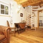 Wohnbereich mit braunem Ledersofa, Holztisch und Wendeltreppe.