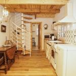 Küche mit Spindeltreppe und Holzboden. Weiße Küchengeräte und Holzdecke.