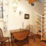 Eckzimmer mit Holztisch, zwei Stühlen und Wendeltreppe.
