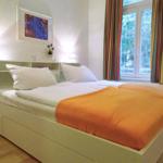 Schlafzimmer mit Doppelbett, Fenster und bunten Vorhängen.