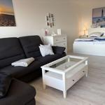 Wohnbereich mit Sofa, Couchtisch und Schlafzimmer mit Bett und Wandbild.