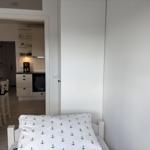 Schlafzimmer mit Bett und Blick in die Küche.