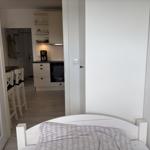 Schlafzimmer mit Bett und Blick in die Küche mit Esstisch.