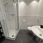 Badezimmer mit Dusche, Toilette und Waschbecken.